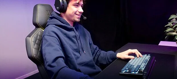 PC gamer sat at a desk, using the keyboard with a satisfied expression