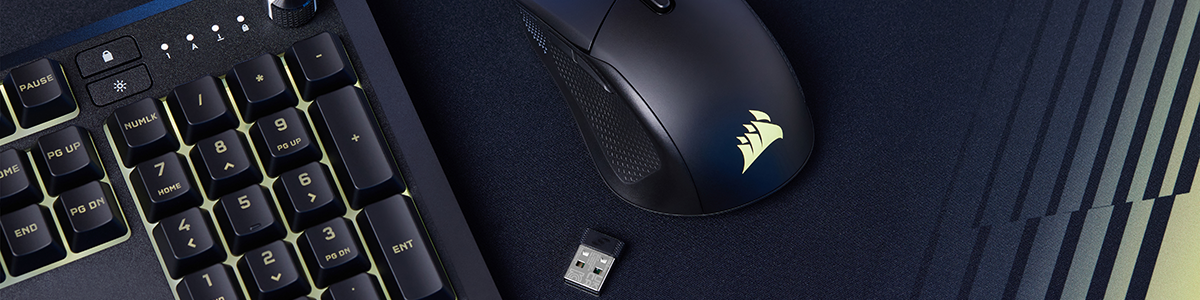 Top down view of mouse, wireless USB receiver and keyboard atop large dark mouse mat.