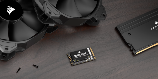 MP600 MICRO SSD atop wooden desk surrounded by Corsair hardware.
