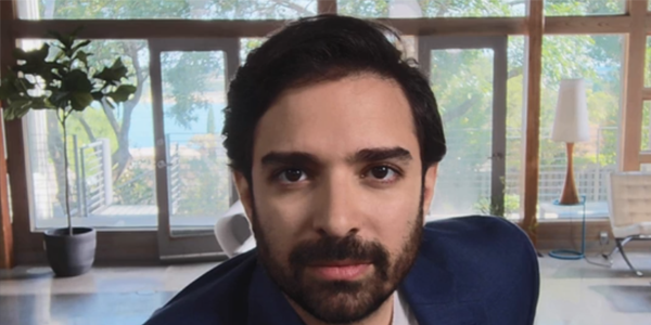 Front angle of bearded businessman in a modern living room with trees visible from the distant windows.