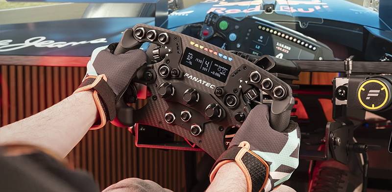 Sim user gripping steering wheel with racing gloves and red bull car visible on screen