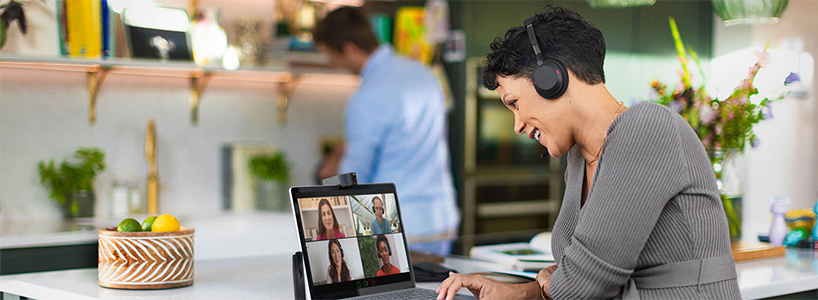Woman having video conference in kitchen wearing Jabra Evolve2 55 headset.