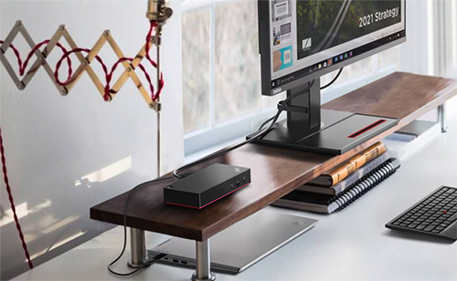 Photography of the ThinkPad dock on a wooden shelf plugged into a computer monitor