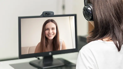 C720 webcam mounted on top of a monitor, with woman sat infront involved in a video call.