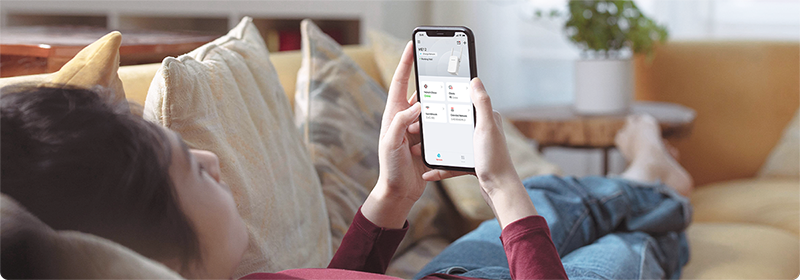 Person lied on sofa with phone in hand, configuring the MERCUSYS app with ease