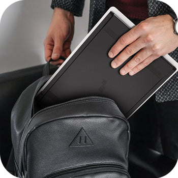 suited person sliding monitor into leather backpack
