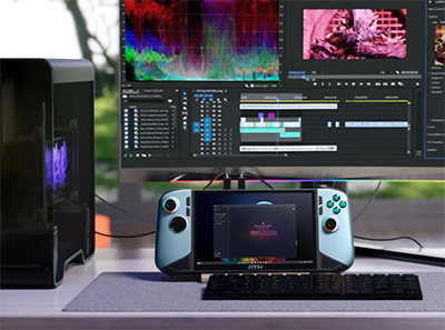 MSI Claw on desktop with video editing software on monitor behind.