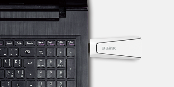 Close up view of top corner of open laptop, with D-Link AX18U WiFi6 adapter plugged into the side.