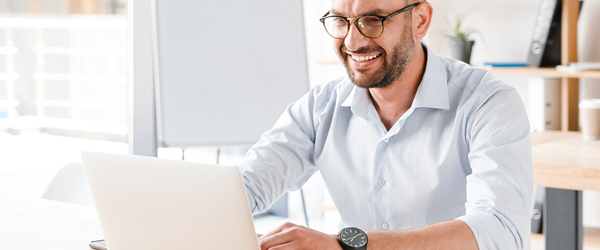 Businessman in modern office working on laptop with AX18U adapter attached.