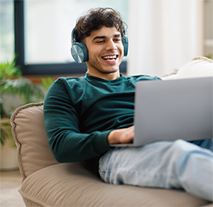 Man lied on sofa, streaming on his laptop.