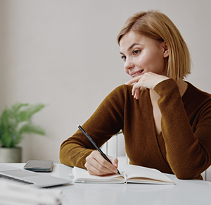 Woman sat behind a desk with a pencil in hand.