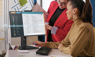 Two office workers reviewing work on angled monitor