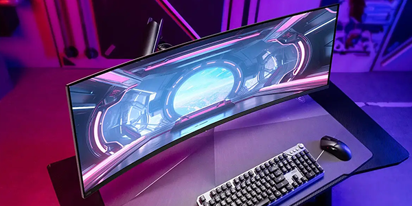 Monitor mounted to arm attached to gaming desk with keyboard and mouse atop.