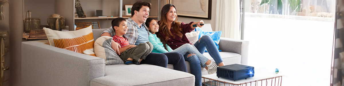 Key visual of UHZ55 projector on coffee table as family sit and watch from their sofa.