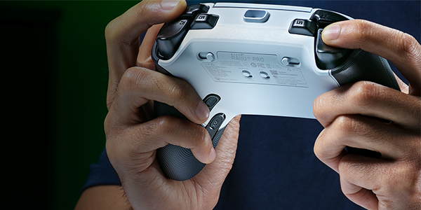 Hands holding Raiju V3 Pro upwards to reveal switches and buttons underneath.