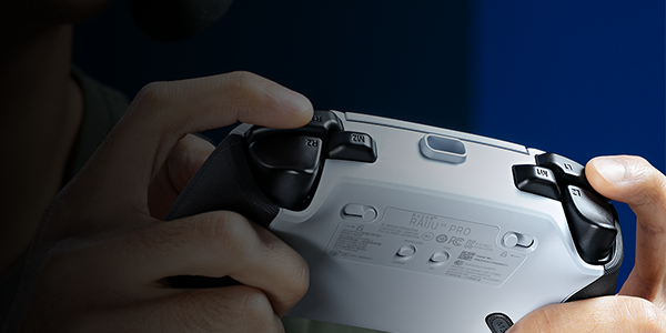 Hands holding Raiju V3 Pro PS5 controller, pressing claw grip bumpers.