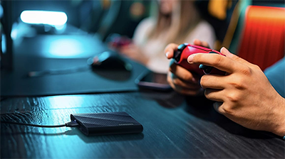 Person holding red controller at desk with SSD in front