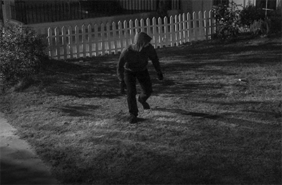 Thief sneaking into front garden. Black and white filter applied to image.