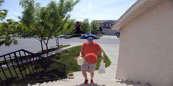Side view of delivery driver placing a parcel on a doorstep, with a blue 140-degree field-of-view overlay beside the doorbell lens.