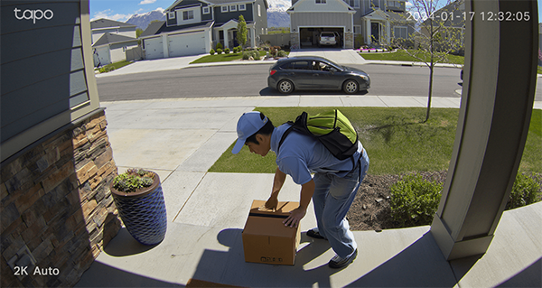 Doorbell view of delivery driver leaving parcel on the doorstep.