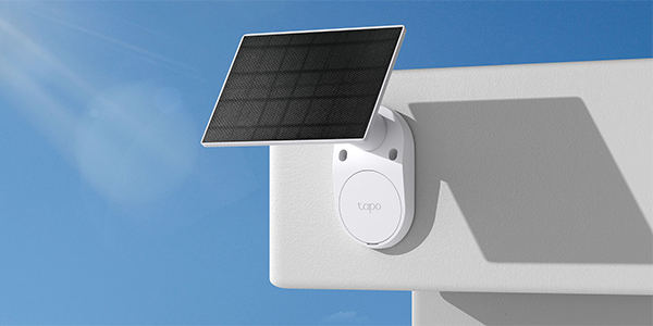 Solar panel attached to corner of a wall with clear blue sky background.
