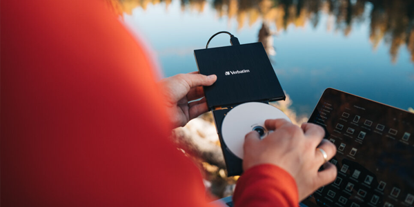 External blu-ray writer in one hand with the other hand pulling the disc tray outward