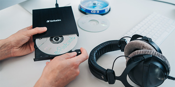External blu-ray writer in one hand with the other hand pulling the disc tray outward