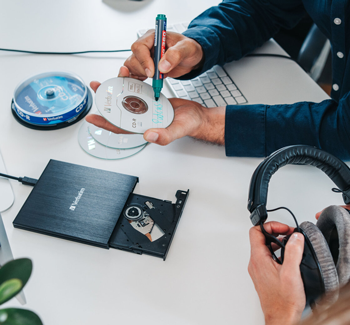 Lifestyle shot showing CD marked 'podcast' being written on with marker while in burner tray