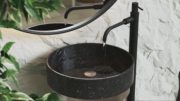 Chaos V-ray still of water simulation flowing from tap into black marble sink