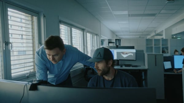 two professionals collaborating in a modern office while viewing 3D models on a computer screen