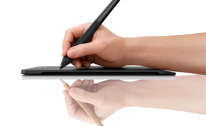 side view of someone drawing on the xencelabs tablet with a reflection of them drawing with pencil and paper