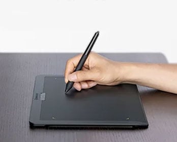 someone drawing on the xencelabs tablet on a wooden desk