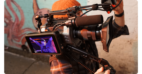 Videographer holding shoulder mounted camera with atomos shogun classic monitor