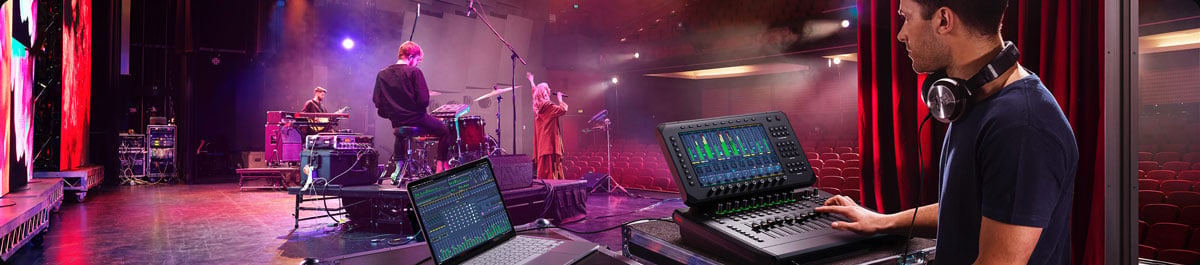 Sound engineer adjusting audio on a mixing console during a live band performance