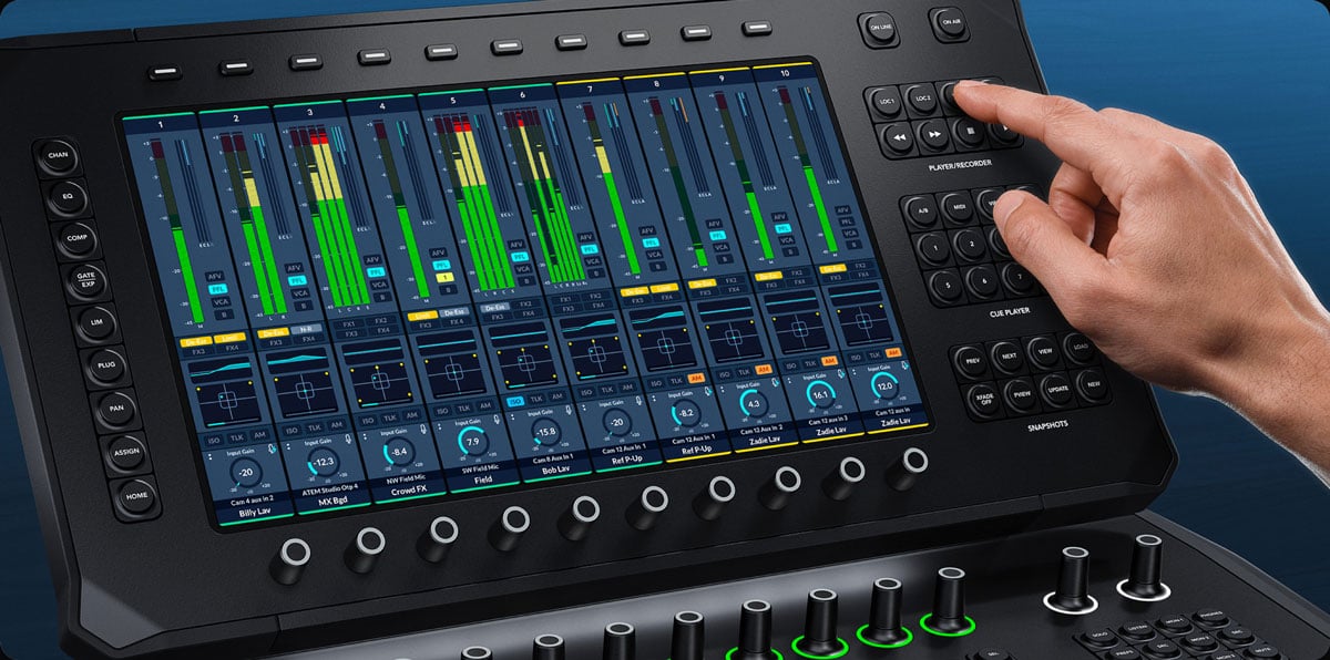 A person operating the Blackmagic Design Fairlight Panel with the touchscreen interface showing multi-channel volume meters