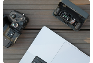 DJI Mic 2 dual microphone set sat on a table with mirrorless camera and macbook pro