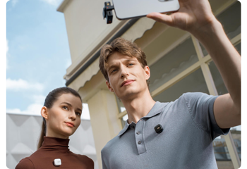 Photograph of two content creators capturing selfie video on iPhone wearing DJI mic Mini Microphones