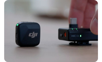 person picking up DJI Mic Mini receiver from next to transmitter