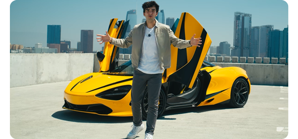Person standing infront of yellow mclaren car at the top of a los angeles car park with city skyline in background