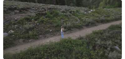 animated gif of woman standing on dirt path being circled by drone