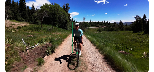 man riding mountain bike along dirt trail with grass and trees on boths sides surrounded by AI tracking overlay