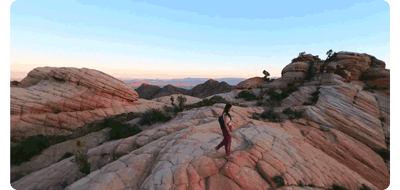 animated gif of woman walking along stone outcrop with Dronie flight path