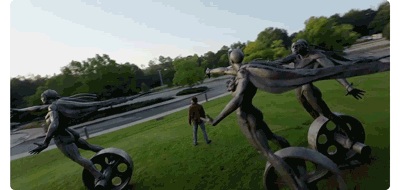 Animated gif of drone circling person standing infront of 3 statues