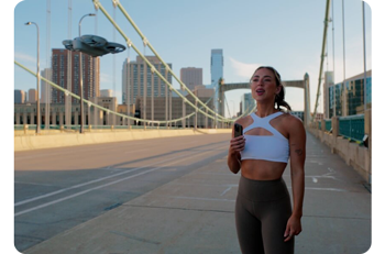 Female fitness influencer using iphone to record audio with DJI Neo Drone