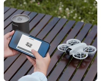 person holding smartphone with DJI Fly App transferring DJI Neo drone on table