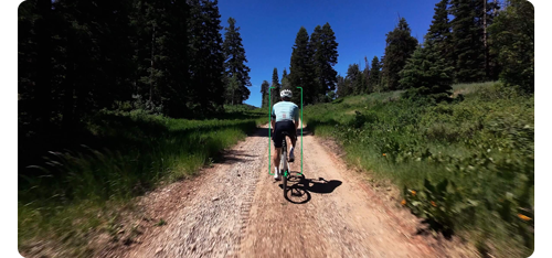 man riding mountain bike along dirt trail with grass and trees on boths sides surrounded by AI tracking overlay