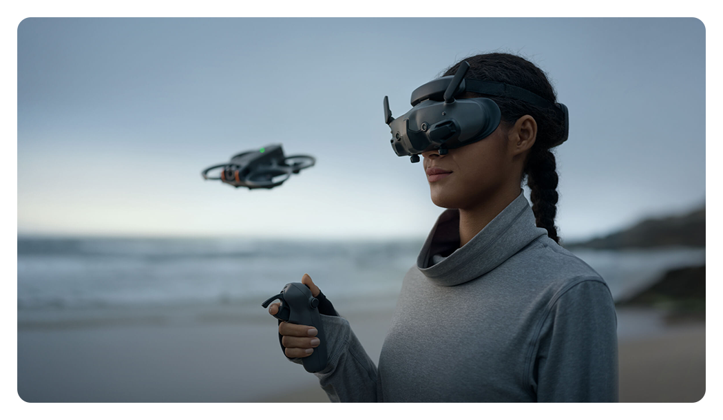 someone using the dji rc motion 3 and goggles 3 to fly a drone on a beach