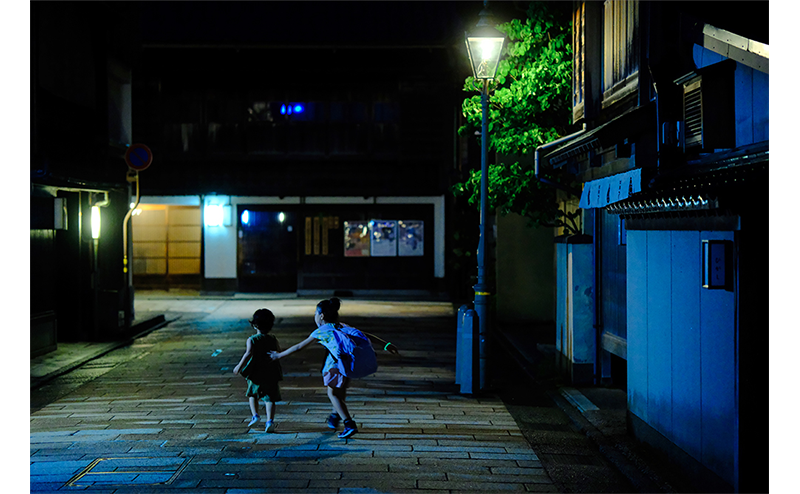 Fujifilm Fujinon XF56mm Lens Sample Image of two children playing in the street at night in japan