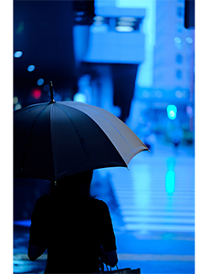 Fujinon XF56mm R WR sample image of person stood under an umbrella in a rainy tokyo street