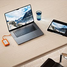 Apple Macbook pro conencted to LaCie Rugged Mini SSD4 on wooden table